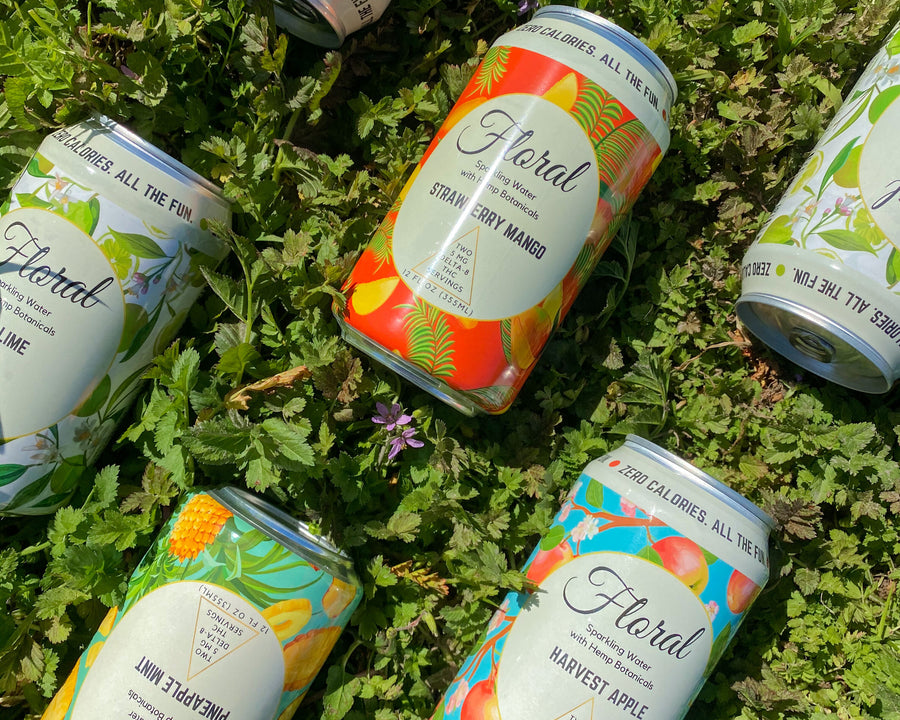 Various flavors of cans of Floral Beverages THC-infused seltzer laying on the grass