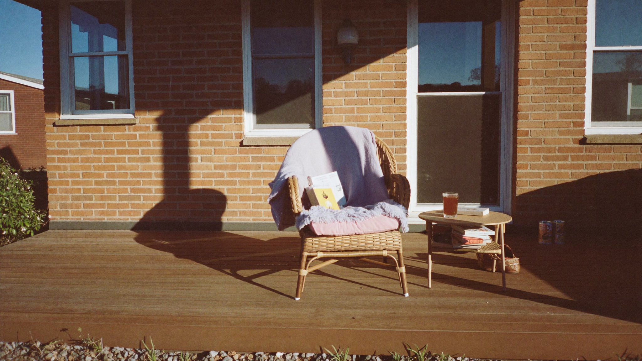 Wicker chair with a blanket and a drink on a side table on a sunny patio