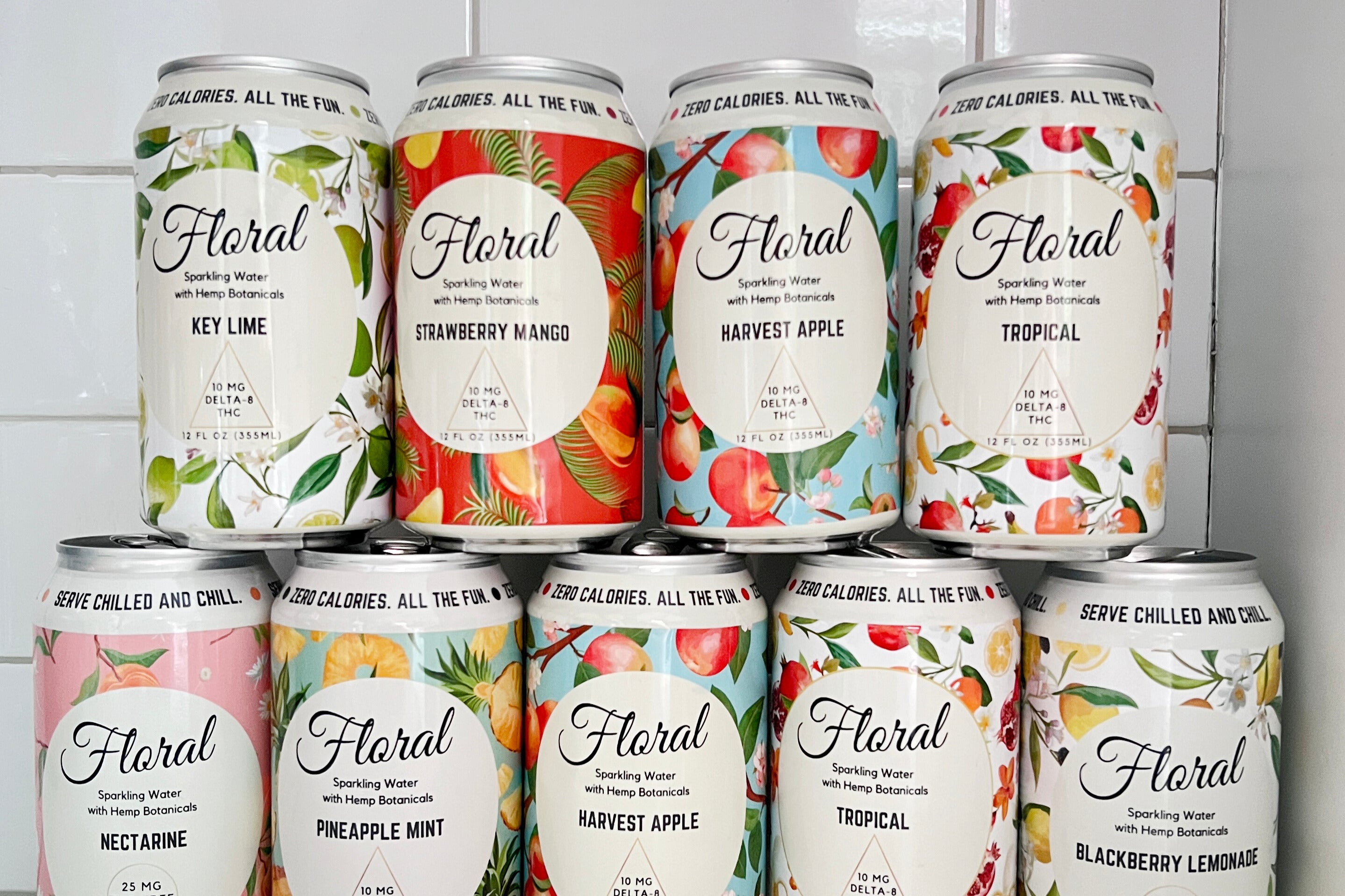 Cans of Floral Beverage's THC Seltzers stacked in various flavors including Key Lime, Strawberry Mango, Harvest Apple, Tropical, Nectarine, Pineapple Mint, and Blackberry Lemonade. 